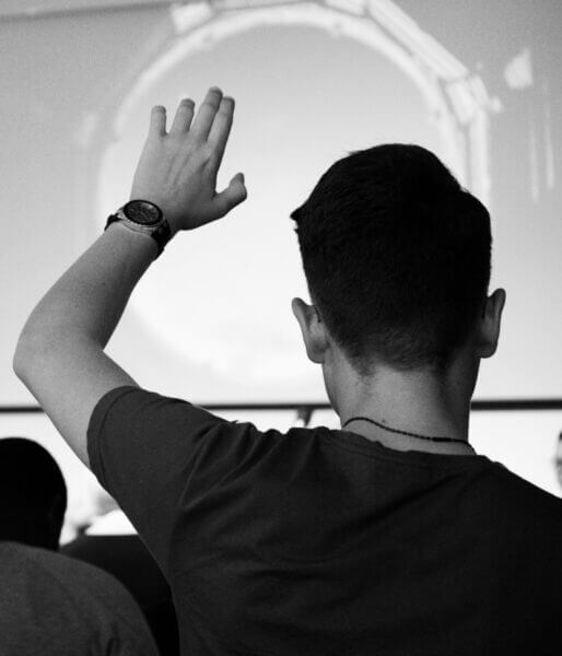 Young man in a christian college program with his hand up worshiping