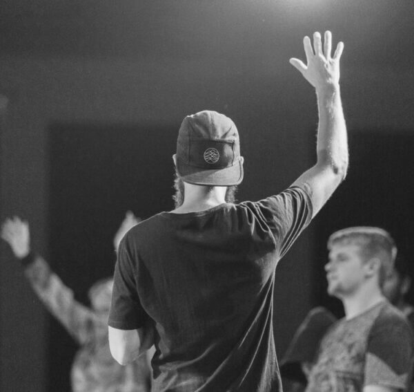 Man standing at his gap year program with his right arm up in the air